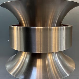 Peut inclure: Un luminaire suspendu en métal argenté au design moderne. La lumière a deux niveaux, chacun avec un abat-jour en forme d'entonnoir.