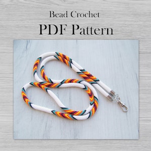 May include: A white beaded lanyard with a black, orange and turquoise chevron pattern. The lanyard has a silver clasp and is labelled "Bead Crochet PDF Pattern".