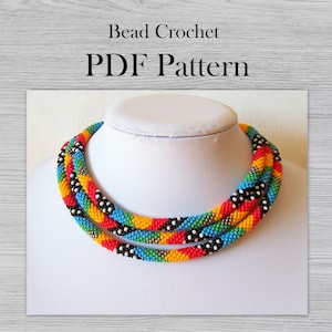Può includere: Una collana di perline colorate con perline nere, bianche, rosse, gialle, blu e verdi. La collana è realizzata con una tecnica all'uncinetto. L'immagine include il testo "Bead Crochet PDF Pattern".