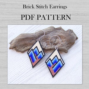 May include: A pair of beaded earrings with a geometric mountain design in shades of blue, white, and black. The earrings are made with brick stitch and are hanging from silver ear wires. The earrings are displayed on a piece of driftwood. PDF PATTERN.