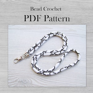 May include: A white and black beaded lanyard with a silver clasp. Bead Crochet PDF Pattern.