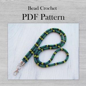 May include: A green, black, and yellow beaded lanyard with silver clasps. Bead Crochet PDF Pattern.