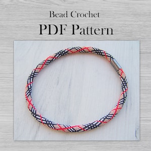 May include: A beaded necklace with a black, white, pink, and red plaid pattern. The necklace is made with small beads and has a magnetic clasp.