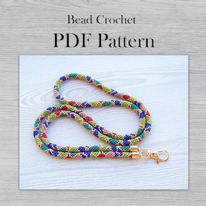 Puede incluir: Un cordón de cuentas de colores con un cierre dorado. El cordón está hecho con cuentas rojas, verdes, azules y doradas. El texto "Bead Crochet PDF Pattern" está en la parte superior de la imagen.