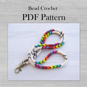 Puede incluir: Un cordón de cuentas colorido con un patrón de chevron blanco y negro y un patrón de zigzag arcoíris. El cordón tiene un cierre de metal. Patrón PDF de crochet de cuentas.