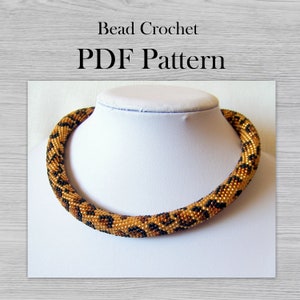 May include: A beaded necklace with a leopard print pattern in shades of gold and black. The necklace is displayed on a white mannequin bust. The text "Bead Crochet PDF Pattern" is displayed above the necklace.