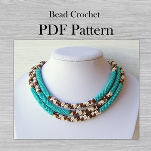 May include: A turquoise, white, and brown beaded necklace with a crocheted design. The necklace is displayed on a white mannequin bust. The text "Bead Crochet PDF Pattern" is displayed above the necklace.