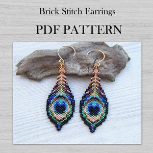 Op de afbeelding: Een paar pauwenveer oorbellen gemaakt met brick stitch beading. De oorbellen hebben een traanvorm met een zwart, blauw, groen en bruin kleurenschema. De oorbellen hangen aan gouden oorhaken.