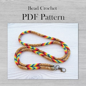 May include: A beaded lanyard with a colorful chevron pattern in shades of brown, red, orange, yellow, turquoise, and blue. The lanyard has a metal clasp and is approximately 36 inches long.