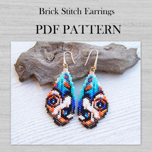 Pode incluir: Um par de brincos em forma de lágrima com um design de rosto de animal colorido. Os brincos são feitos com pequenas contas coloridas em um padrão de ponto de tijolo. Os brincos estão sobre uma superfície de madeira. O texto "Brick Stitch Earrings PDF PATTERN" está na parte superior da imagem.