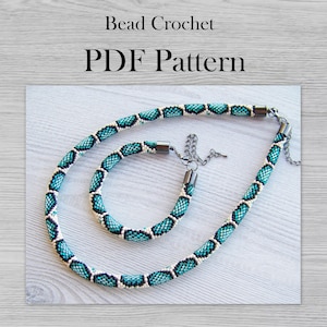 Könnte beinhalten: Ein türkisfarbenes und weißes Perlen-Halsketten- und Armband-Set mit Magnetverschlüssen. Das Set ist aus kleinen Perlen gefertigt und hat ein schlangenartiges Muster. Perlen-Häkel-PDF-Muster.