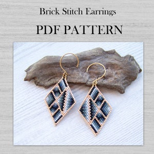 May include: A pair of black, white, and gray diamond-shaped earrings with gold hooks. The earrings are made with brick stitch beading and are hanging from a piece of driftwood. The text "PDF PATTERN" is written in black letters on a white background.