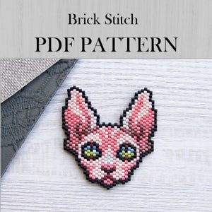 May include: A beaded cat face in pink, black, and white, with green and blue eyes. The text "Brick Stitch PDF PATTERN" is displayed above the cat. The cat is made of small beads.