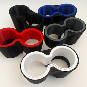 May include: Four different color cup holders, each with a black base and a different colored inner ring. The colors are red, blue, gray, and white.