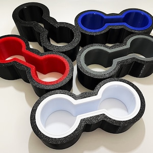 May include: Five black and white double-ended cup holders with different colored inner rings. The rings are red, blue, gray, and white.