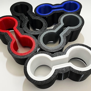 May include: Five 3D printed black plastic holders with different colored inner rings. The holders are shaped like a figure eight with two circular openings. The colors of the inner rings are red, blue, gray, and white.