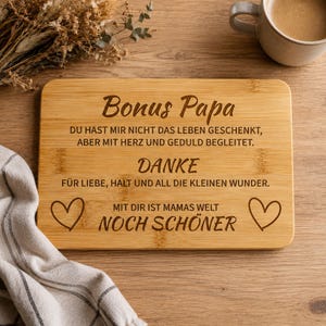 Può includere: Un tagliere rettangolare in bambù con un'incisione laser in tedesco che recita: Bonus Papa, Du hast mir nicht das Leben geschenkt, aber mit Herz und Geduld begleitet. Danke für Liebe, Halt und all die kleinen Wunder. Mit dir ist Mamas Welt noch schöner, decorato con due cuori.