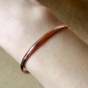 Könnte beinhalten: Ein schlichtes Armband aus Roségold am Handgelenk.