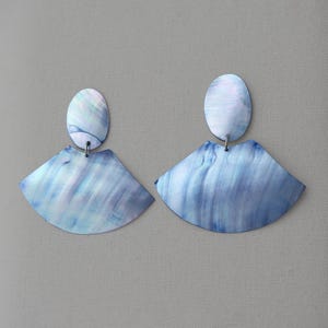 May include: A pair of blue iridescent earrings with a fan-shaped design. The earrings are made of a smooth, shiny material.