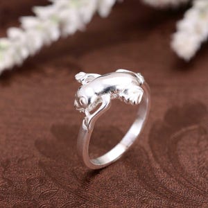 Op de afbeelding: Een zilveren ring met een kikkerontwerp. De kikker zit op de ringband.