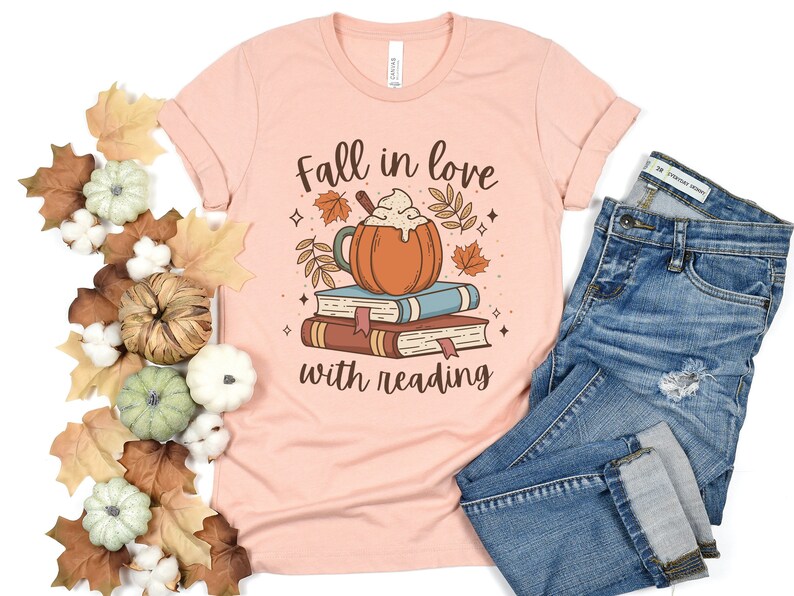 Pode incluir: Uma camiseta cor de p&ecirc;ssego com o texto "Apaixone-se pela leitura" e um gr&aacute;fico de um latte de especiarias de ab&oacute;bora em cima de uma pilha de livros.