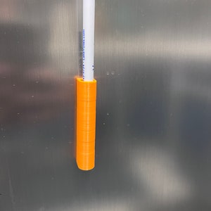 May include: A white dry-erase marker with blue text that reads "800-774-LakeYotes.com" is held in place by an orange 3D printed holder.