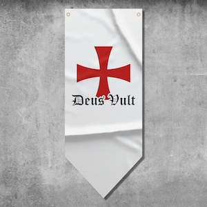 May include: White banner with a red cross design and the words "Deus Vult" in black gothic lettering. The banner has a pointed bottom and two grommets at the top for hanging. The background is a textured gray wall.