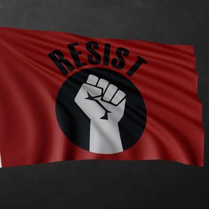 May include: A rectangular red flag featuring a central black circle containing a white graphic of a raised fist. The word RESIST is printed in black capital letters in an arc above the circle. The flag has two metal grommets on the left side.