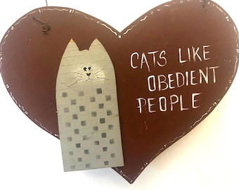 May include: A brown heart-shaped wooden sign with a gray cat illustration and the text "Cats like obedient people".