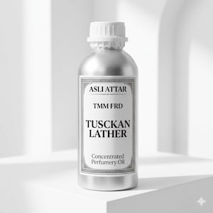 May include: A silver-colored bottle with a white cap. The label reads "ASLI ATTAR," "TMM FRD," and "TUSCKAN LATHER." Below, it says "Concentrated Perfumery Oil." The bottle is likely a container for fragrance or essential oil.