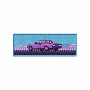 Op de afbeelding: Een rechthoekige geborduurde patch met een paarse coupé-auto gecentreerd tegen een lichtblauwe lucht en een donkere, getextureerde ondergrond. Het ontwerp bevat roze wolken aan de horizon en is omlijst door een lichtblauwe rand met zichtbare stiksels.