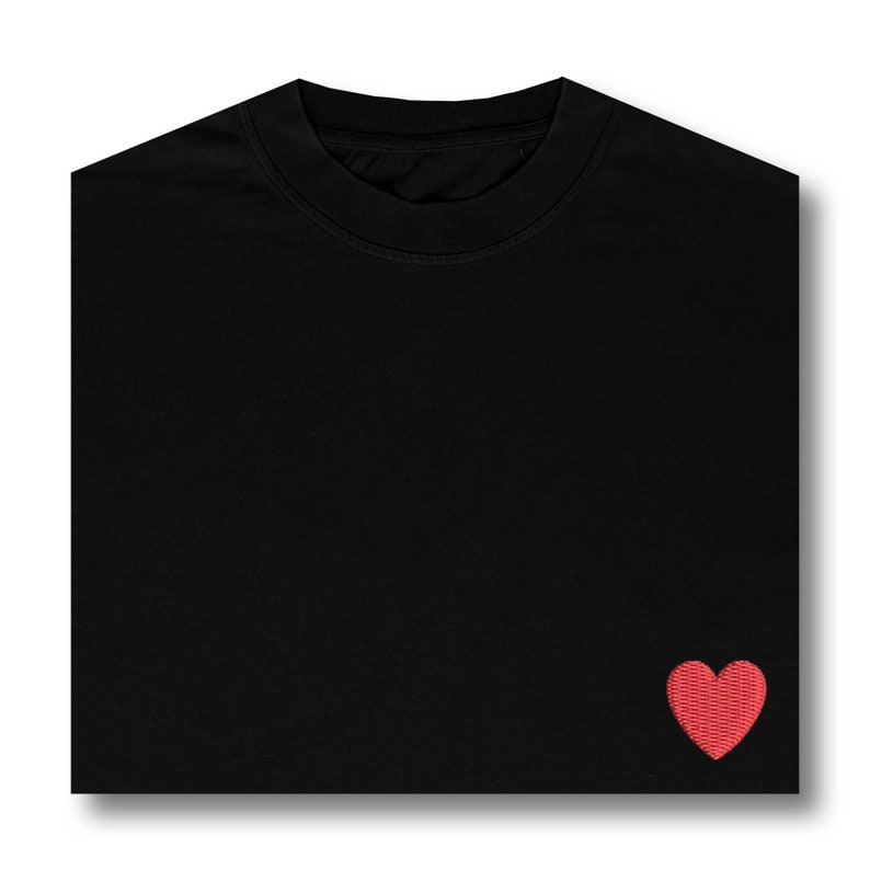 May include: A black t-shirt with a small red heart embroidered on the right side of the chest.