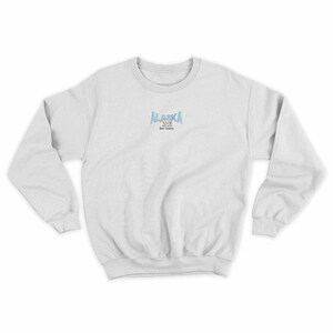 May include: A white sweatshirt with a blue and white graphic of a bear and the text "ALASKA Bear Country" on the front.