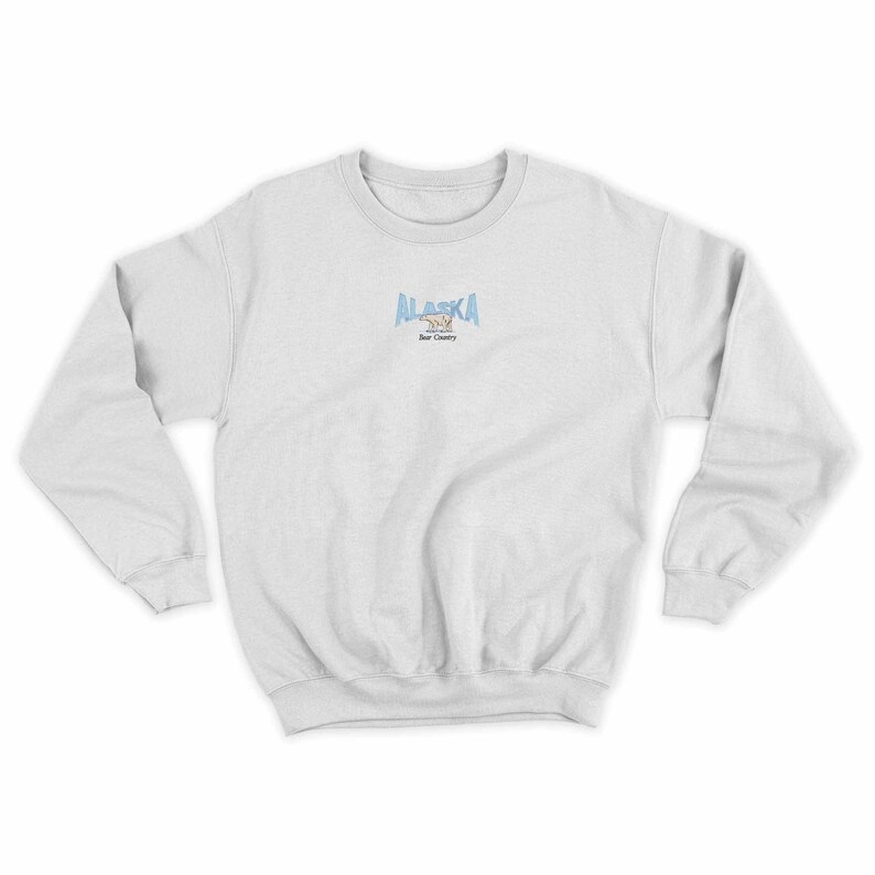 May include: A white sweatshirt with a blue and white graphic of a bear and the text "ALASKA Bear Country" on the front.