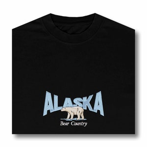 May include: Black t-shirt with a blue and white graphic of a polar bear walking on ice with the text "Alaska Bear Country" underneath.