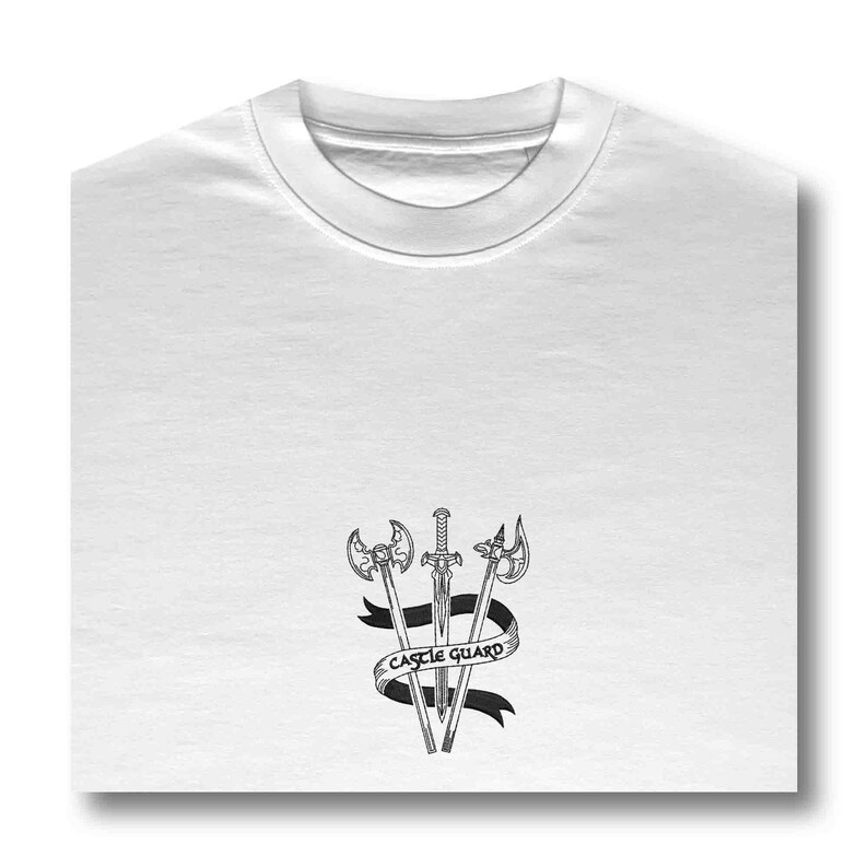 K&ouml;nnte beinhalten: Wei&szlig;es T-Shirt mit einer schwarz-wei&szlig;en Grafik von drei Schwertern und einer Axt mit einem Banner, auf dem "Castle Guard" steht.