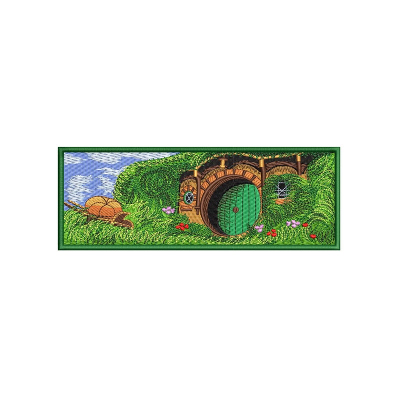 An embroidered patch depicting a hobbit hole with a green door, surrounded by lush green grass and flowers. A small cart with two round objects is in the foreground.