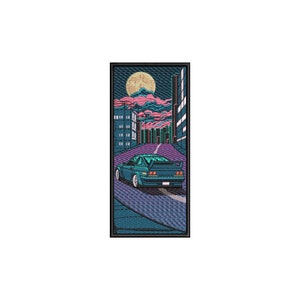 May include: A blue car drives down a street at night with a full moon in the sky. The street is lined with buildings and the car has a spoiler on the back.