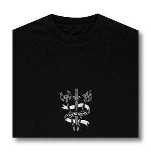 K&ouml;nnte beinhalten: Schwarzes T-Shirt mit einer wei&szlig;en Grafik von drei Schwertern und einer Axt mit einem Banner, auf dem "CASTLE GUARD" steht.