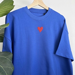 May include: A royal blue t-shirt with a small red embroidered heart on the front.