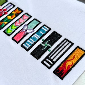 以下が含まれることがあります： ハート、蝶、ストライプ、渦巻き、炎など、さまざまなデザインの刺繍パッチが並んでいます。パッチはすべて黒で縁取られており、白い背景に配置されています。