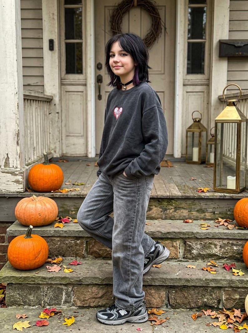 Dark oversized sweatshirt featuring a small red and white skeleton love heart embroidery on the chest, styled in a gothic autumn outfit.