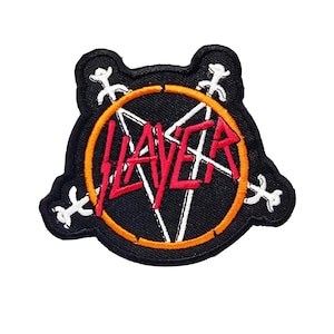 Puede incluir: Parche bordado negro y naranja con la palabra "Slayer" en letras rojas y un diseño de pentagrama.