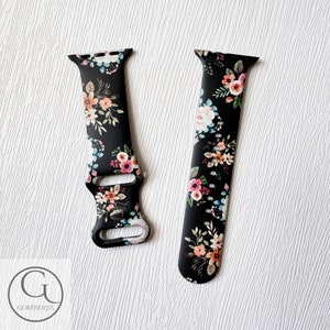 May include: Black silicone Apple Watch band with a floral print featuring pink, orange, and blue flowers. The band has a black buckle and is compatible with Apple Watch Series 4 and later.