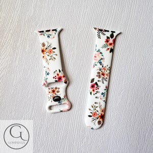 May include: White silicone watch band with a floral pattern in shades of pink, orange, and green. The band is designed for Apple Watch.