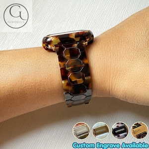 May include: A watch band featuring a brown and black tortoiseshell pattern with a link-style design. The band is composed of interconnected hexagonal segments. Four small circular thumbnails at the bottom display metal clasps with the text GOBANDZUS.