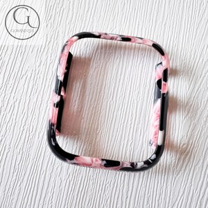 Puede incluir: Una funda protectora rectangular para reloj con un patr&oacute;n de m&aacute;rmol en tonos negro, blanco y rosa suave. El marco tiene esquinas redondeadas y un acabado liso y brillante, dise&ntilde;ado para cubrir la pantalla y los bordes de un reloj digital.