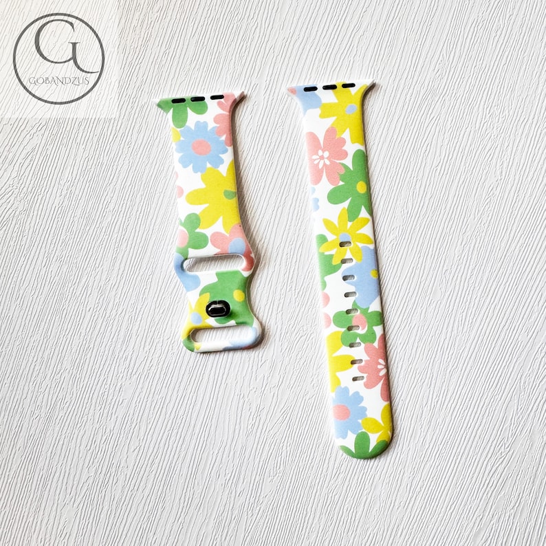 May include: White Apple Watch band with a floral pattern in shades of pink, yellow, blue, and green.
