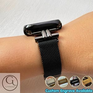 Könnte beinhalten: Ein schwarzes Uhrenarmband aus Metallgeflecht mit einem polierten schwarzen Verbindungsstück. Das Armband weist eine feine, gewebte Textur und einen sicheren Verschlussmechanismus auf. Das Design ist schlicht und funktional für ein Gerät am Handgelenk.