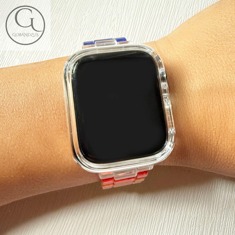 May include: A smartwatch with a clear, transparent protective case and a multi-colored link band featuring segments of blue, clear, and coral-red. The watch face is black and rectangular with rounded corners, displaying no visible icons or text.